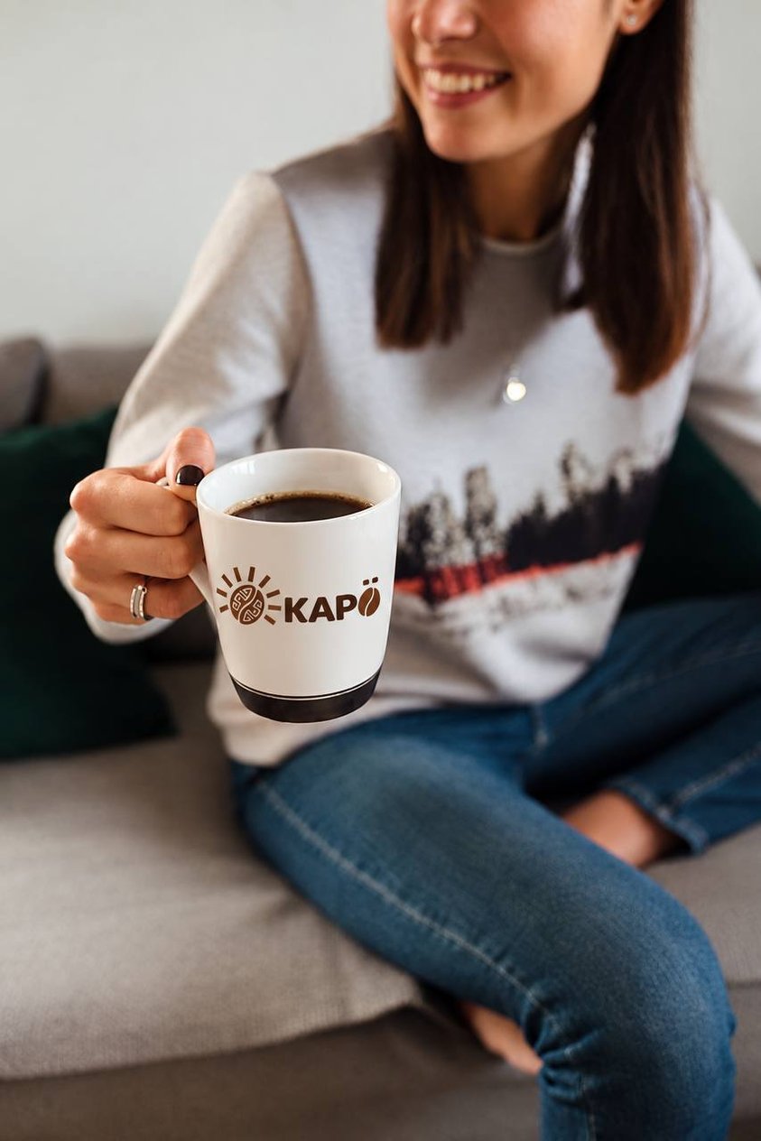 Persona sonriendo con una taza de Café Kapö recién servida