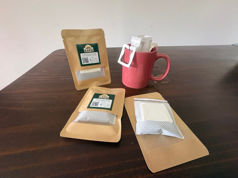 Sobres de chorreador portátil Café Kapö sobre una mesa, junto a una taza